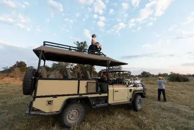 Group gathered around safari vehicles at sunrise